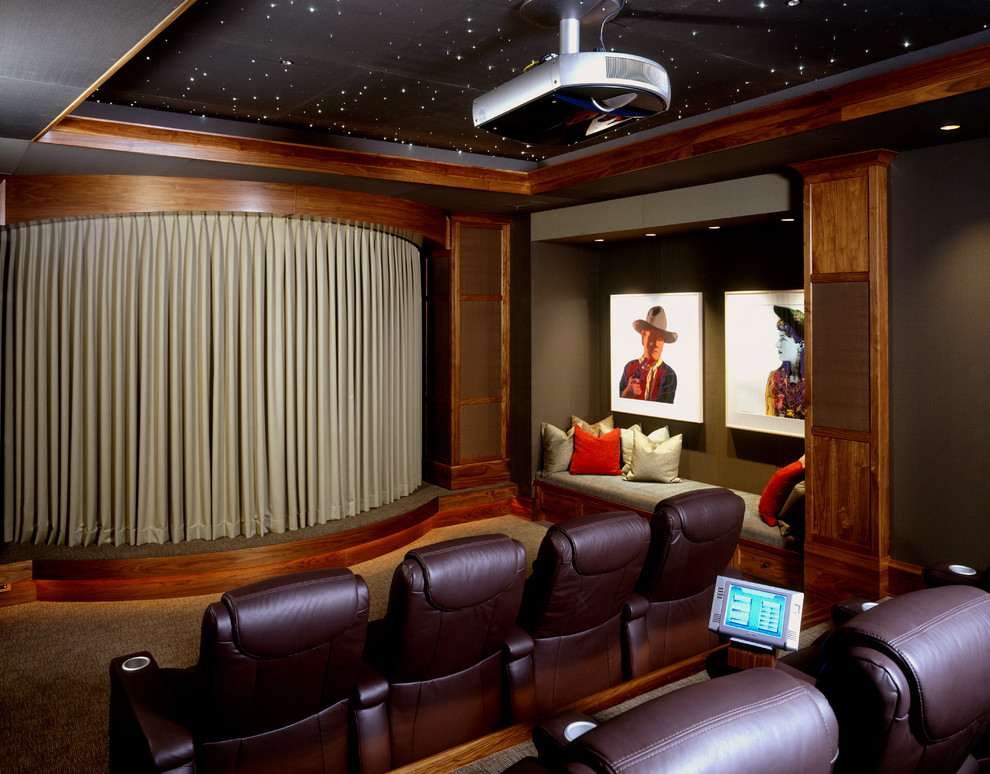 This is an example of a traditional enclosed home theatre in Minneapolis with black walls, carpet and a projector screen.