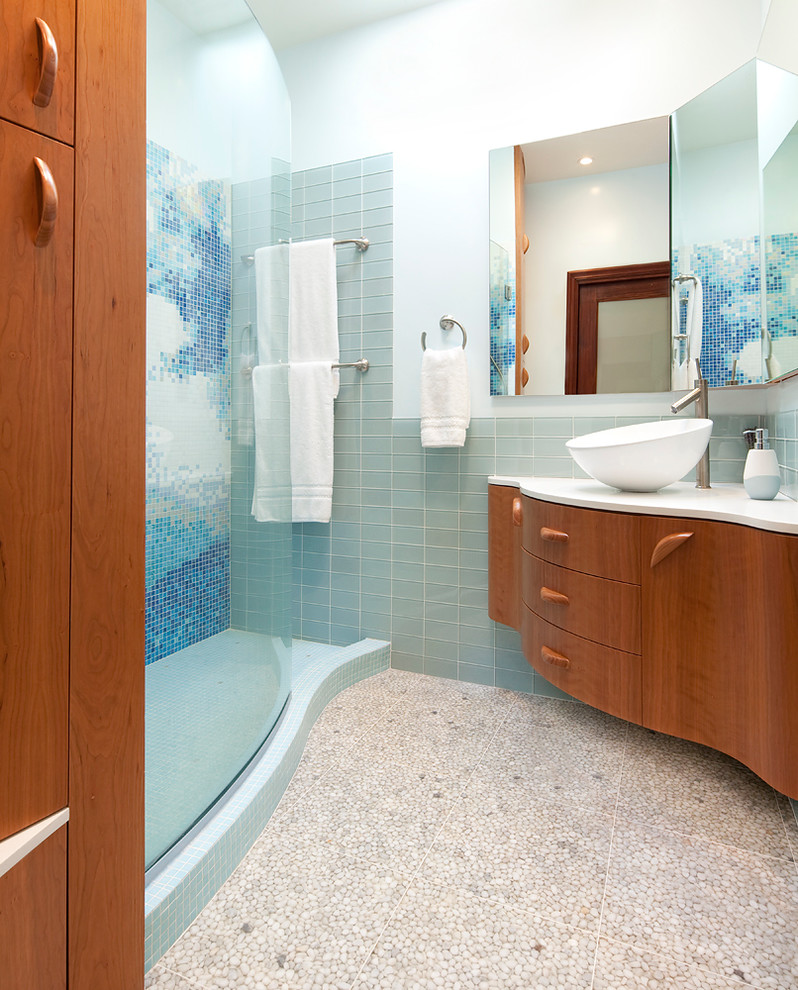 Design ideas for a mid-sized contemporary 3/4 bathroom in San Francisco with a vessel sink, flat-panel cabinets, medium wood cabinets, engineered quartz benchtops, an open shower, a wall-mount toilet, blue tile, glass tile, white walls, pebble tile floors, an alcove tub, beige floor and a hinged shower door.