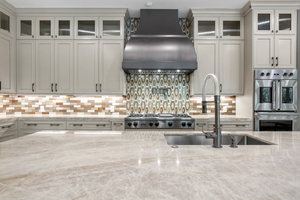 This is an example of a large transitional l-shaped eat-in kitchen in Houston with an undermount sink, recessed-panel cabinets, beige cabinets, quartzite benchtops, brown splashback, glass tile splashback, stainless steel appliances, cement tiles, with island, grey floor and beige benchtop.