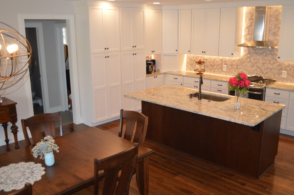 Inspiration for a large transitional l-shaped dark wood floor eat-in kitchen remodel in Charlotte with a single-bowl sink, flat-panel cabinets, white cabinets, granite countertops, gray backsplash, mosaic tile backsplash, stainless steel appliances and an island
