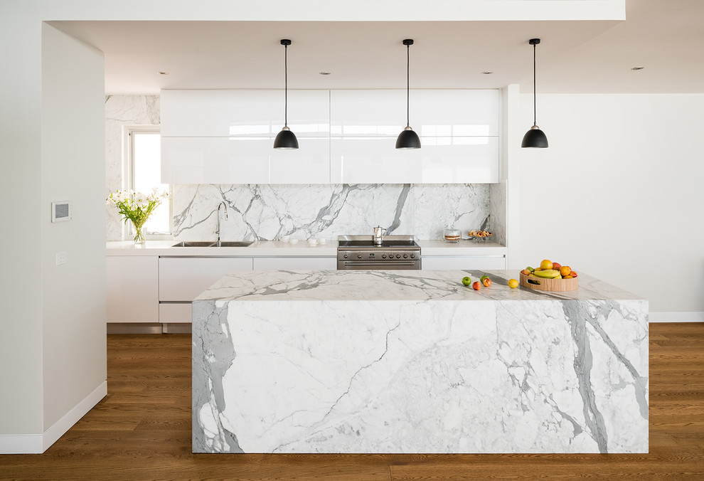 Contemporary kitchen in Melbourne with flat-panel cabinets, white cabinets, white splashback, medium hardwood floors, with island and marble splashback.