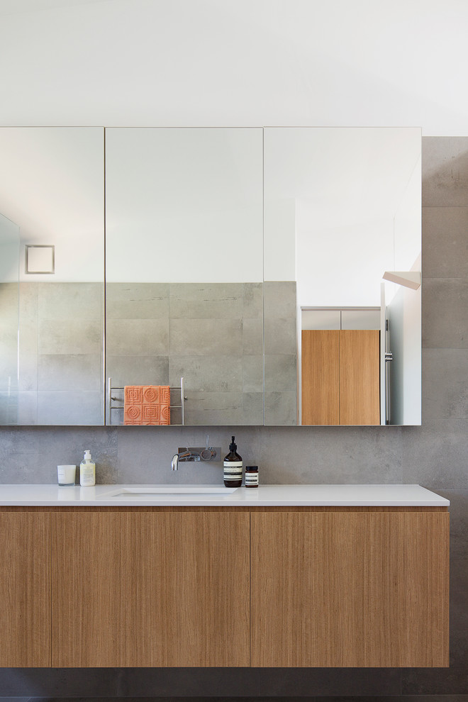 Large contemporary master bathroom in Sydney with light wood cabinets, a curbless shower, gray tile, porcelain tile, grey walls, ceramic floors, an undermount sink and solid surface benchtops.
