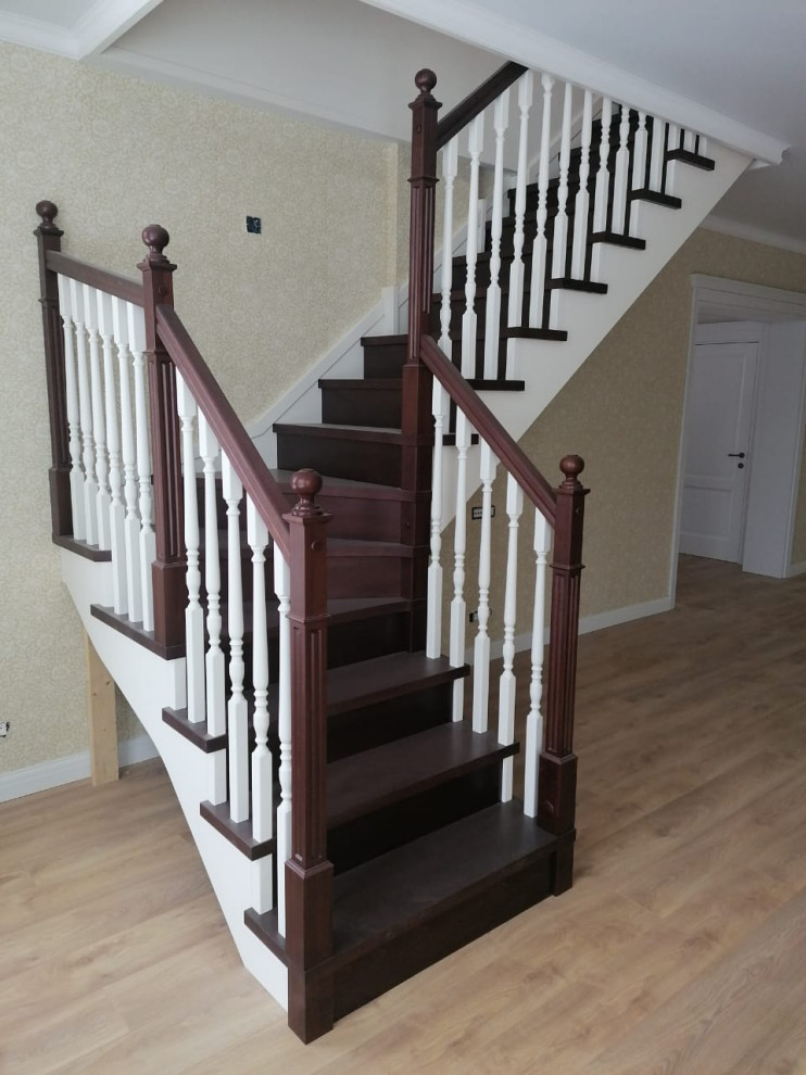 Diseño de escalera en U tradicional de tamaño medio con escalones de madera, contrahuellas de madera, barandilla de madera y papel pintado