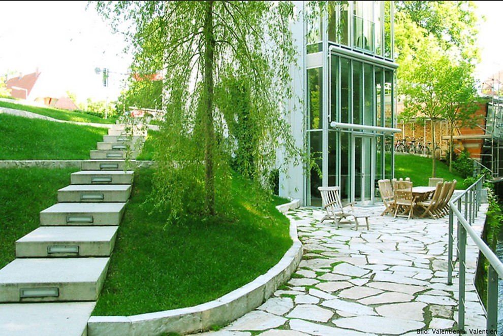 Photo of a large contemporary sloped garden in Munich with natural stone pavers.