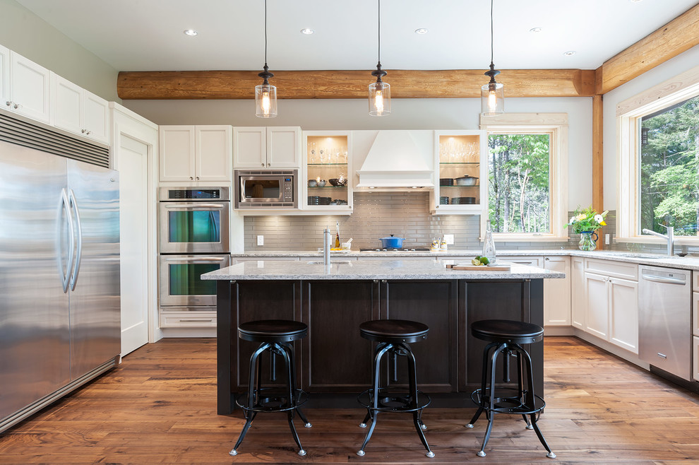 Design ideas for a transitional kitchen in Vancouver with recessed-panel cabinets, white cabinets, grey splashback, subway tile splashback, stainless steel appliances, medium hardwood floors and with island.