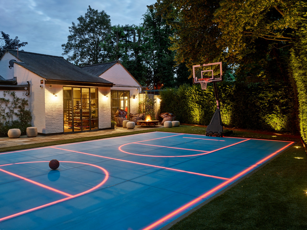 Photo of an eclectic backyard outdoor sport court in London with a fire feature and natural stone pavers.