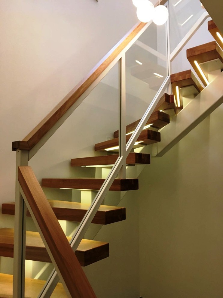 Cette image montre un grand escalier courbe design avec des marches en bois.