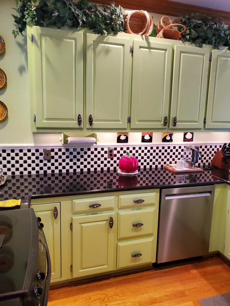 Foto på ett mellanstort vintage svart kök, med en dubbel diskho, skåp i shakerstil, gröna skåp, granitbänkskiva, rostfria vitvaror, ljust trägolv, en halv köksö och gult golv