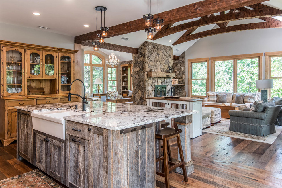 Mid-sized country u-shaped eat-in kitchen in Other with a farmhouse sink, shaker cabinets, distressed cabinets, granite benchtops, white splashback, porcelain splashback, black appliances, medium hardwood floors, with island, brown floor and grey benchtop.