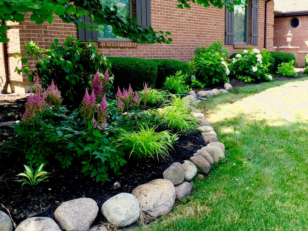 This is an example of a mid-sized transitional front yard partial sun garden for summer in Chicago with a garden path and natural stone pavers.