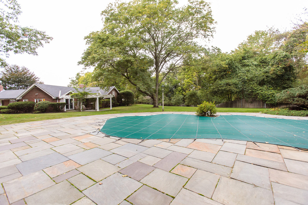 Large country backyard custom-shaped natural pool in Boston with natural stone pavers.