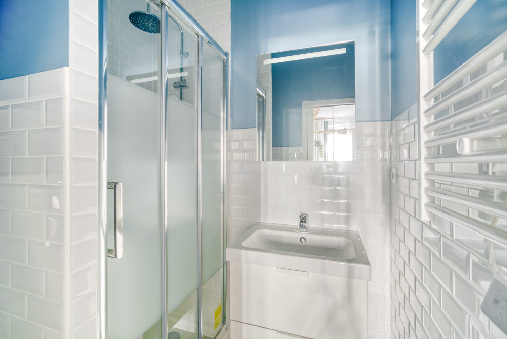 Idée de décoration pour une petite salle d'eau nordique avec un placard à porte affleurante, des portes de placard blanches, une douche à l'italienne, WC suspendus, un carrelage blanc, un carrelage métro, un mur bleu, un sol en carrelage de céramique, un lavabo posé, une cabine de douche à porte coulissante, un plan de toilette blanc, meuble simple vasque et meuble-lavabo suspendu.