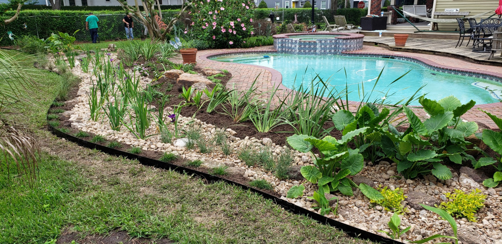 This is an example of a mid-sized contemporary backyard full sun garden in Houston with river rock.