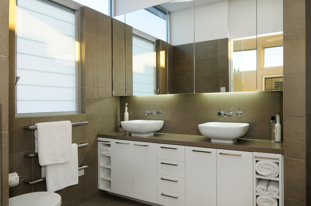 Photo of a large contemporary master bathroom in Sydney with flat-panel cabinets, white cabinets, a freestanding tub, an open shower, a one-piece toilet, brown tile, porcelain tile, blue walls, travertine floors, a vessel sink, engineered quartz benchtops, brown floor, an open shower and brown benchtops.