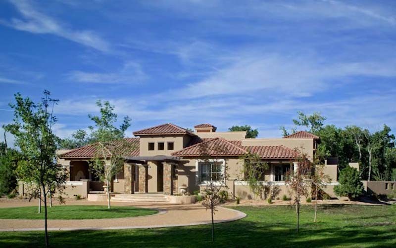 Photo of an expansive mediterranean one-storey stucco beige house exterior in Albuquerque with a gable roof and a tile roof.
