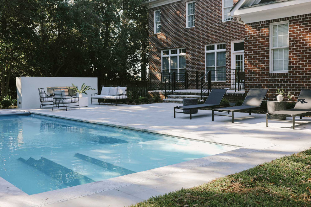 Modelo de piscina alargada moderna grande rectangular en patio trasero con paisajismo de piscina y adoquines de piedra natural