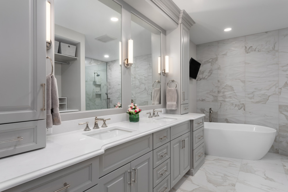 Design ideas for a large traditional ensuite bathroom in St Louis with raised-panel cabinets, grey cabinets, a freestanding bath, a walk-in shower, white tiles, porcelain tiles, grey walls, porcelain flooring, a submerged sink, engineered stone worktops, white floors, an open shower, white worktops, a laundry area, double sinks and a built in vanity unit.