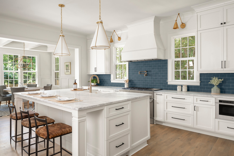 Open concept kitchen - large transitional l-shaped medium tone wood floor open concept kitchen idea in Charlotte with a farmhouse sink, marble countertops, blue backsplash, subway tile backsplash, stainless steel appliances, an island and white countertops
