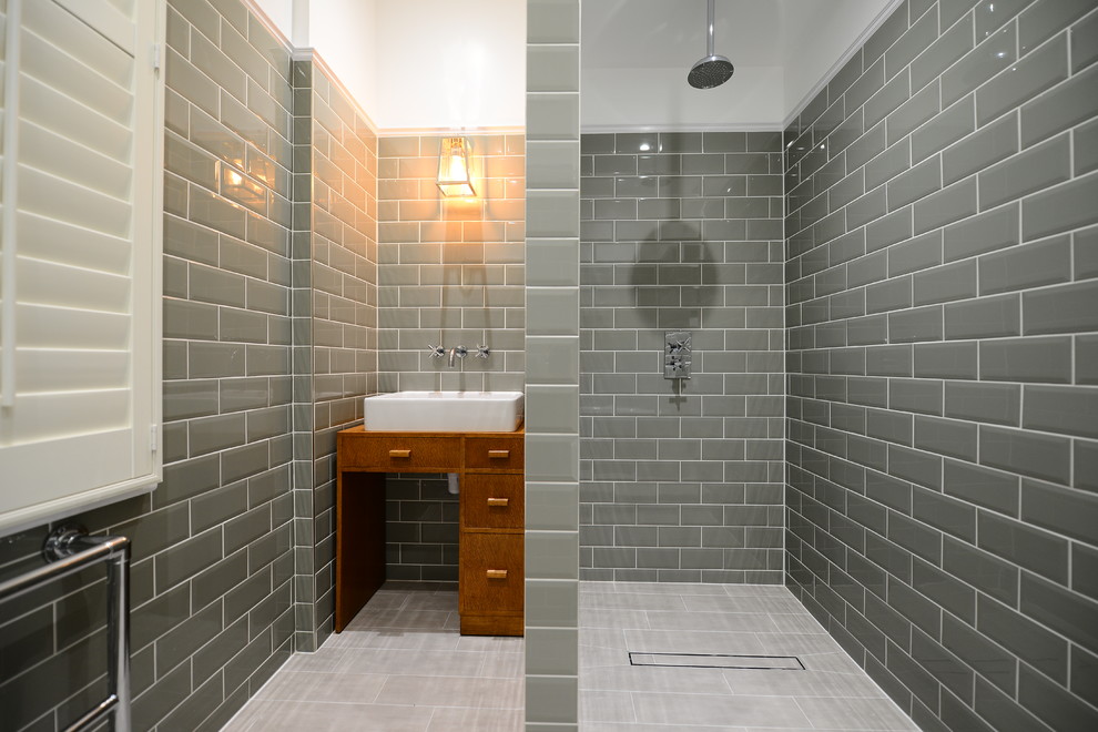 Inspiration for a mid-sized transitional master bathroom in London with medium wood cabinets, porcelain floors, a vessel sink, an open shower, gray tile, subway tile, an open shower and flat-panel cabinets.