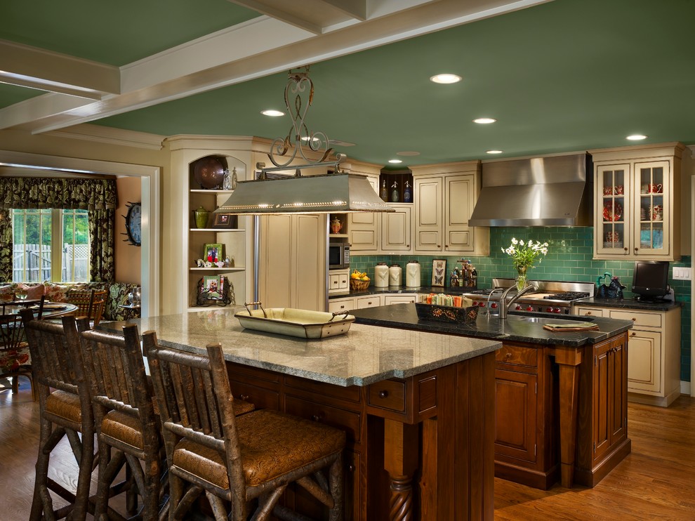 Design ideas for a country galley open plan kitchen in Philadelphia with an undermount sink, raised-panel cabinets, distressed cabinets, soapstone benchtops, green splashback, subway tile splashback, stainless steel appliances, light hardwood floors and multiple islands.