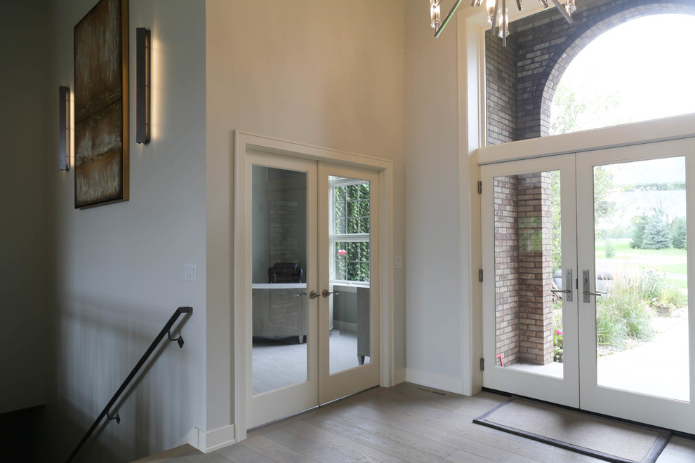 Example of a mid-sized transitional light wood floor and beige floor foyer design with gray walls and a glass front door