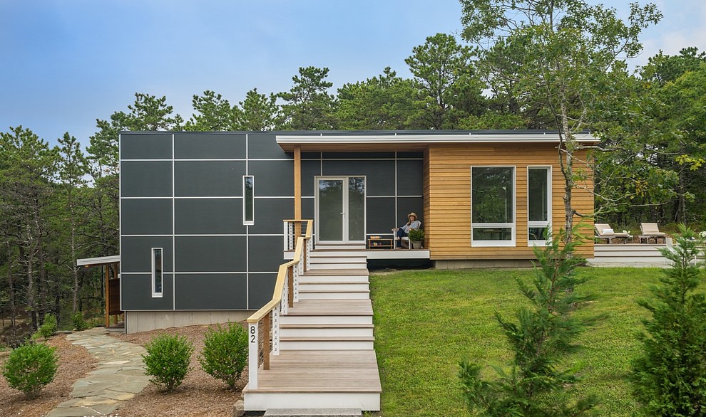 This is an example of a small contemporary two-storey black house exterior in Boston with a flat roof and mixed siding.