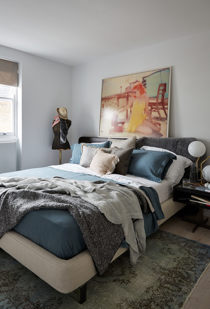 Inspiration for a medium sized eclectic guest bedroom in London with white walls, light hardwood flooring and no fireplace.
