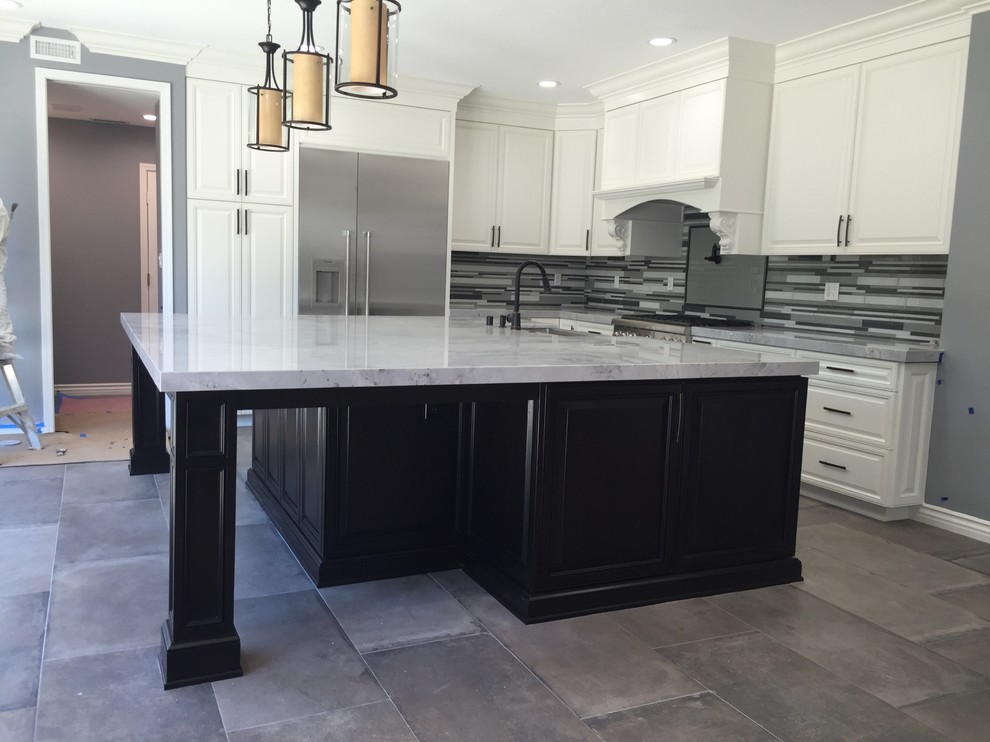 Photo of a mid-sized transitional l-shaped separate kitchen in Los Angeles with an undermount sink, raised-panel cabinets, white cabinets, marble benchtops, matchstick tile splashback, stainless steel appliances, slate floors, with island and grey splashback.