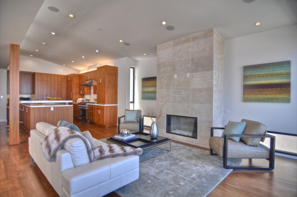 This is an example of a contemporary open concept living room in Los Angeles with white walls, medium hardwood floors and a standard fireplace.