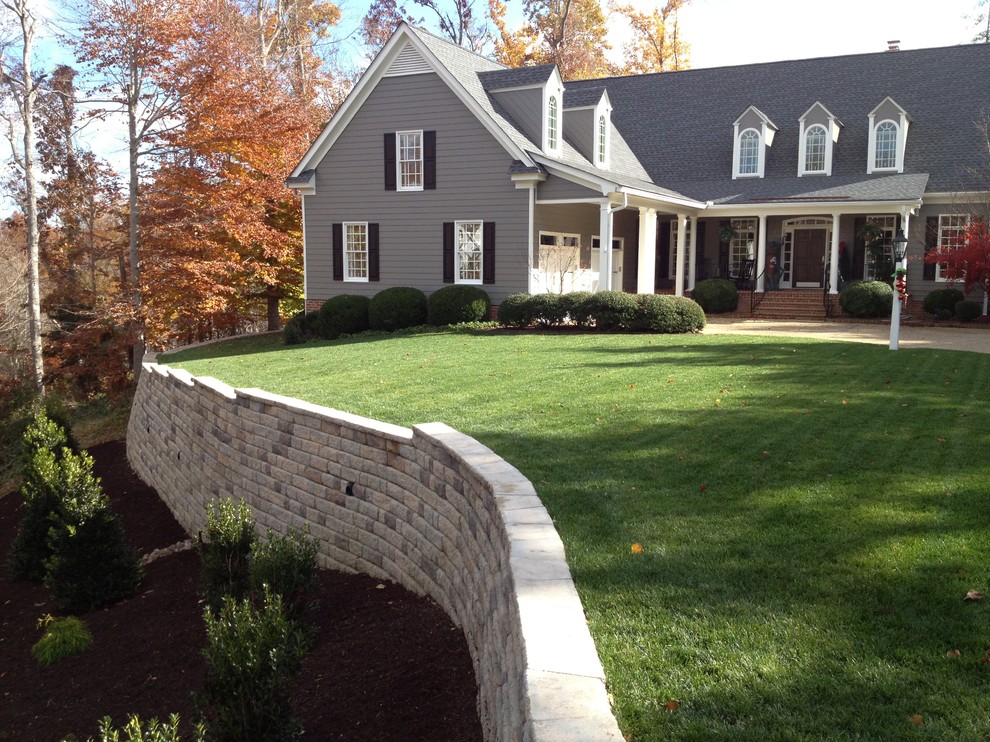 Mid-sized transitional sloped full sun garden in Other with a retaining wall and natural stone pavers for fall.