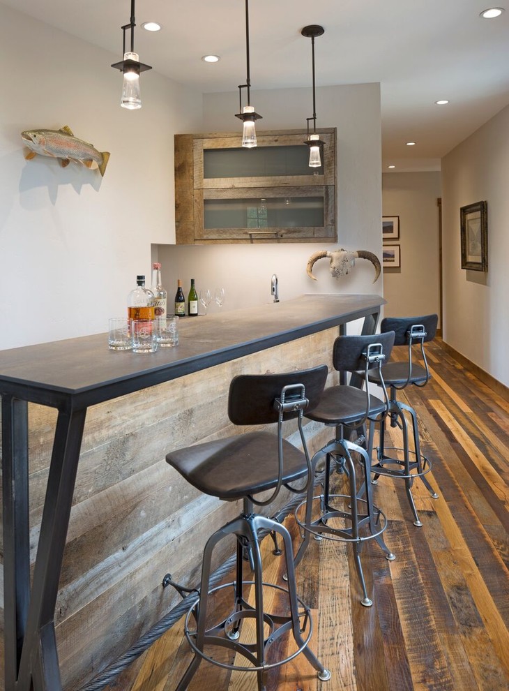 Photo of a large country galley seated home bar in Denver with a drop-in sink, glass-front cabinets, dark wood cabinets, concrete benchtops, white splashback, stone slab splashback and dark hardwood floors.