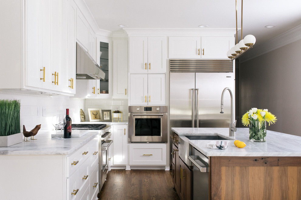 Photo of a large transitional l-shaped eat-in kitchen in Atlanta with a farmhouse sink, shaker cabinets, white cabinets, marble benchtops, white splashback, ceramic splashback, stainless steel appliances, dark hardwood floors and with island.