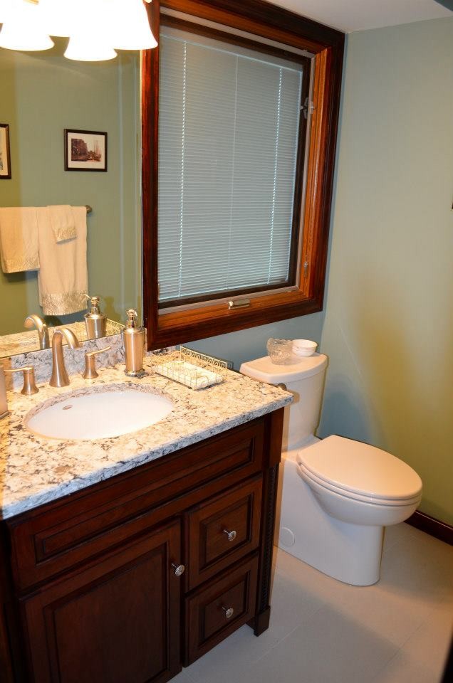 Photo of a traditional powder room in New York with an undermount sink, raised-panel cabinets, dark wood cabinets, engineered quartz benchtops, a two-piece toilet and beige tile.