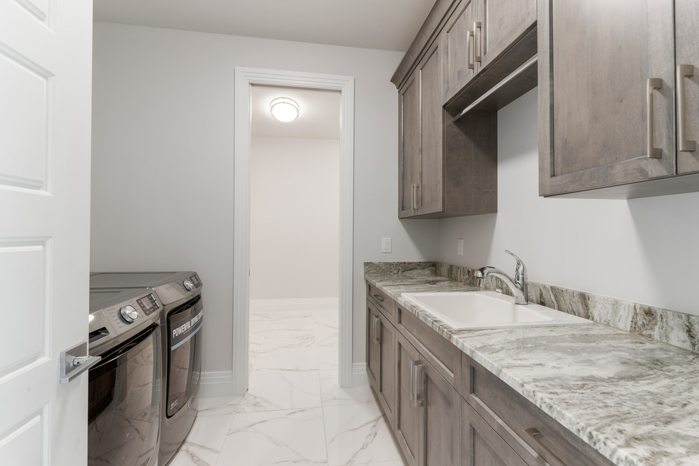 Mid-sized contemporary galley dedicated laundry room in Other with a drop-in sink, recessed-panel cabinets, dark wood cabinets, granite benchtops, grey walls, porcelain floors, a side-by-side washer and dryer, multi-coloured floor and multi-coloured benchtop.