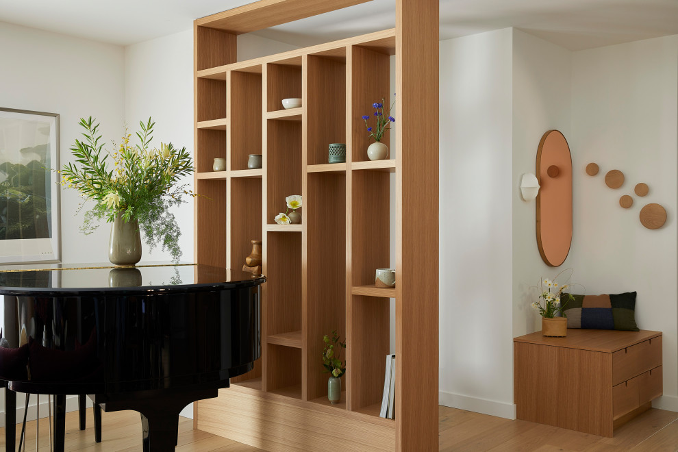 Example of a small trendy light wood floor and brown floor entryway design in San Francisco with white walls and a medium wood front door
