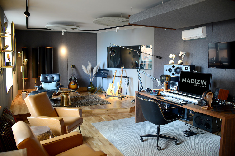 This is an example of an expansive contemporary home studio in Hamburg with grey walls, light hardwood flooring, a freestanding desk, brown floors, wallpapered walls and feature lighting.