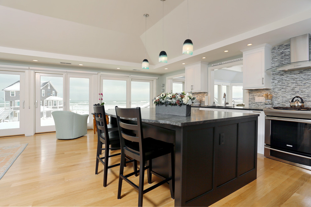 Mid-sized transitional l-shaped light wood floor open concept kitchen photo in Boston with white cabinets, granite countertops, an island, an undermount sink, shaker cabinets, gray backsplash, matchstick tile backsplash and stainless steel appliances