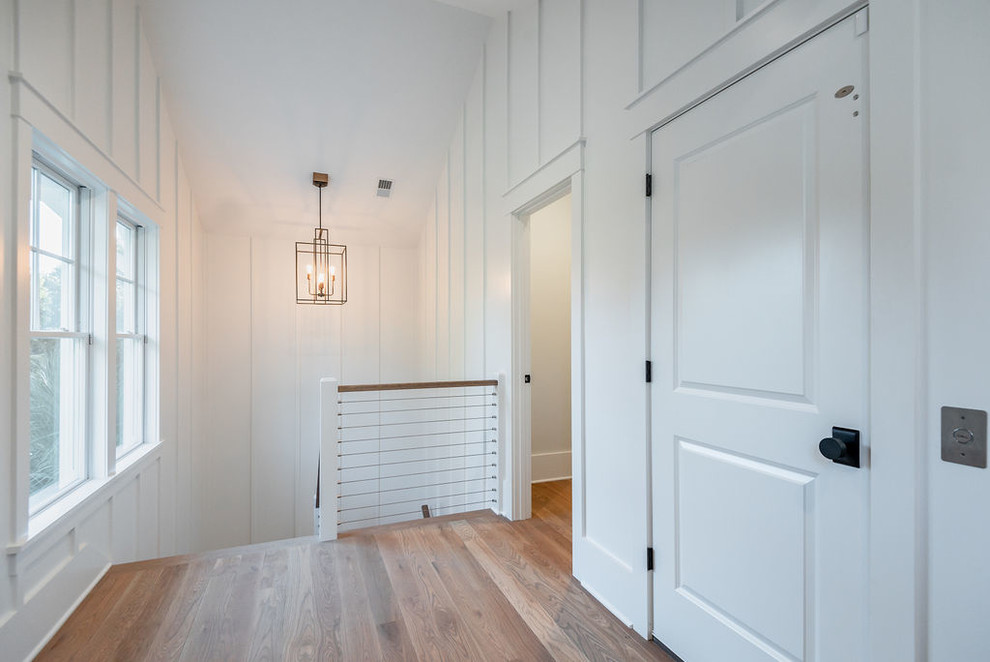 This is an example of a mid-sized beach style hallway in Charleston with white walls, medium hardwood floors and brown floor.