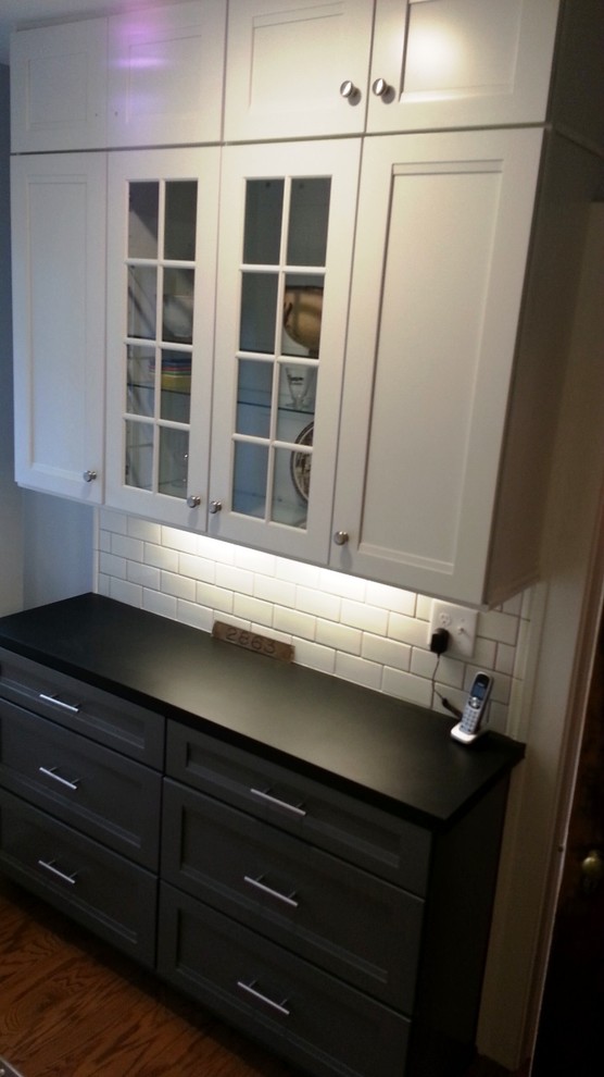 Mid-sized transitional u-shaped dark wood floor and brown floor enclosed kitchen photo in Cleveland with an undermount sink, shaker cabinets, white cabinets, gray backsplash, stainless steel appliances, quartz countertops, mosaic tile backsplash, no island and gray countertops
