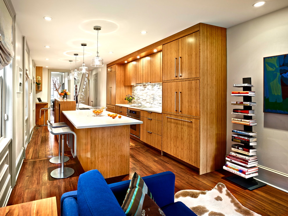 Design ideas for a mid-sized contemporary galley open plan kitchen in Philadelphia with flat-panel cabinets, medium wood cabinets, dark hardwood floors, with island, a drop-in sink, marble benchtops, white splashback, stone tile splashback, stainless steel appliances and brown floor.