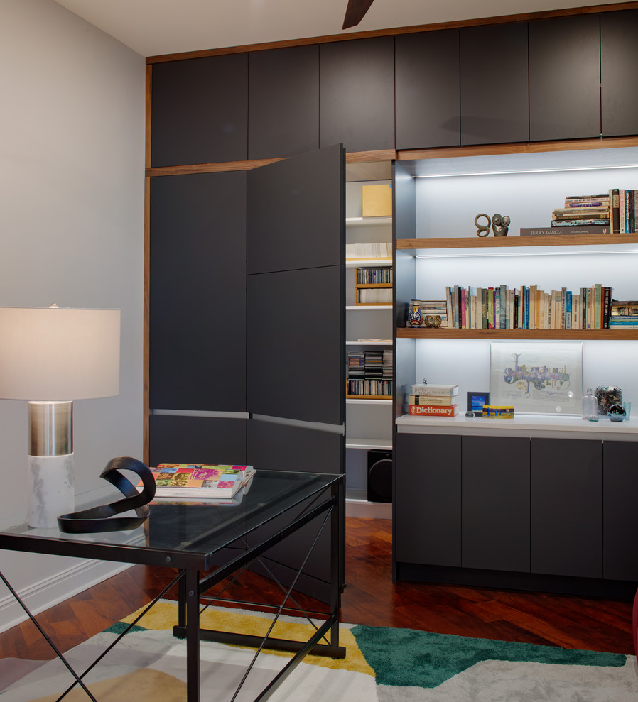 Inspiration for a large modern home office in Other with a library, white walls, dark hardwood floors, no fireplace, a freestanding desk and red floor.