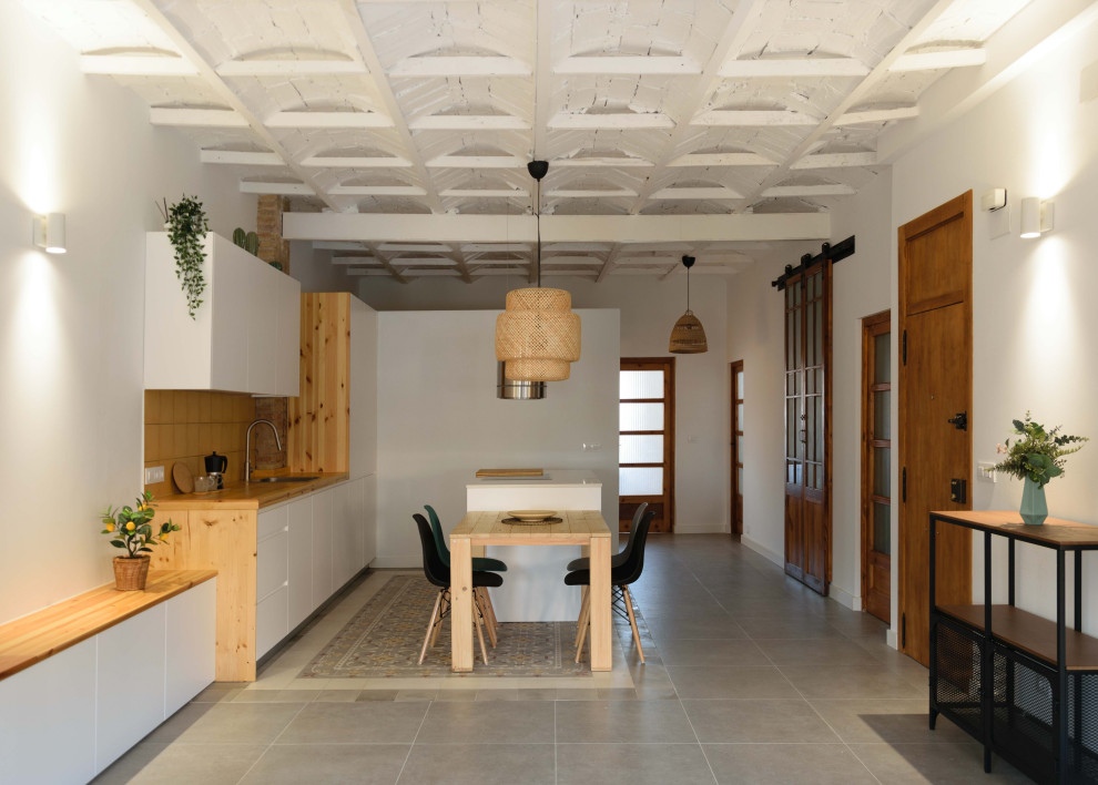 Design ideas for a mid-sized mediterranean single-wall open plan kitchen in Valencia with a single-bowl sink, flat-panel cabinets, white cabinets, yellow splashback, ceramic splashback, ceramic floors, with island, grey floor and vaulted.