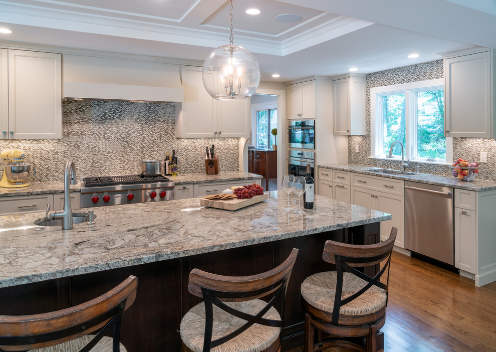 Inspiration for a transitional l-shaped dark wood floor and brown floor kitchen remodel in Boston with white cabinets, mosaic tile backsplash, stainless steel appliances, an island, an undermount sink, shaker cabinets, gray backsplash and gray countertops
