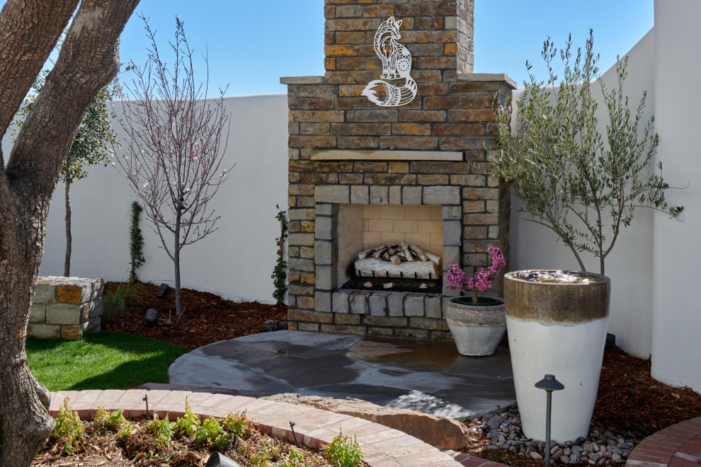 This is an example of a small bohemian courtyard xeriscape garden in Other with a fireplace and natural stone paving.