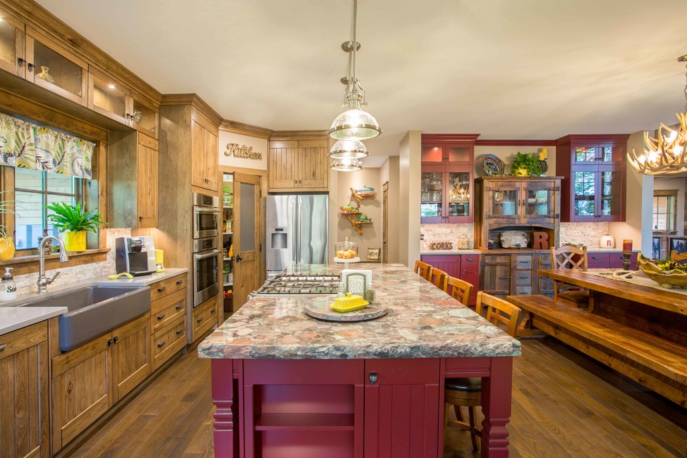Mid-sized country u-shaped eat-in kitchen in Other with a farmhouse sink, shaker cabinets, medium wood cabinets, quartz benchtops, stone tile splashback, stainless steel appliances, medium hardwood floors, with island, brown floor, multi-coloured benchtop and beige splashback.