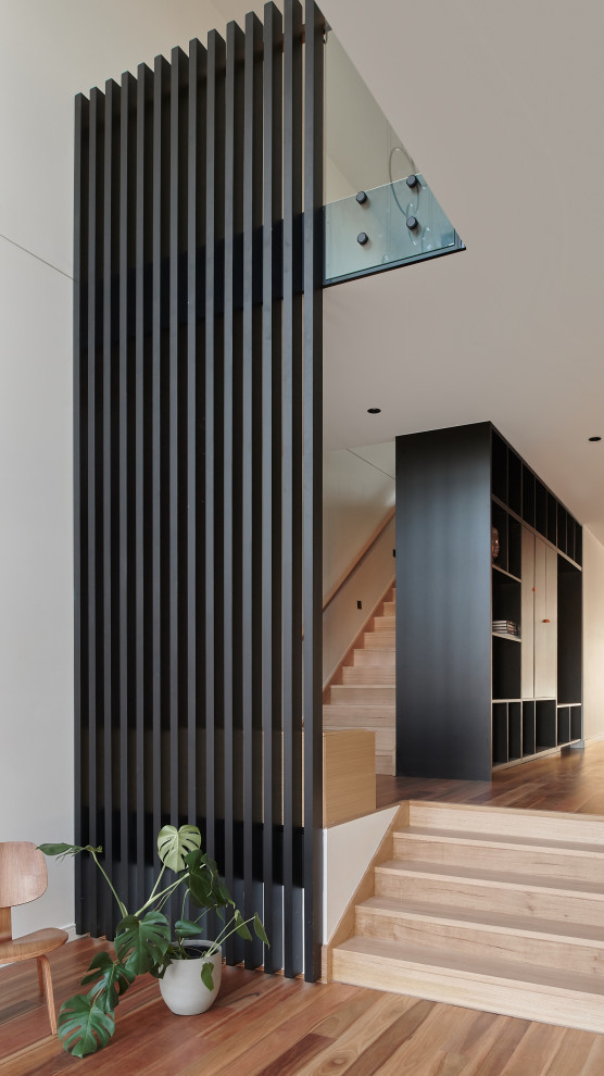 Photo of a mid-sized contemporary foyer in Melbourne with a pivot front door, a brown front door, panelled walls, white walls, medium hardwood floors and orange floor.