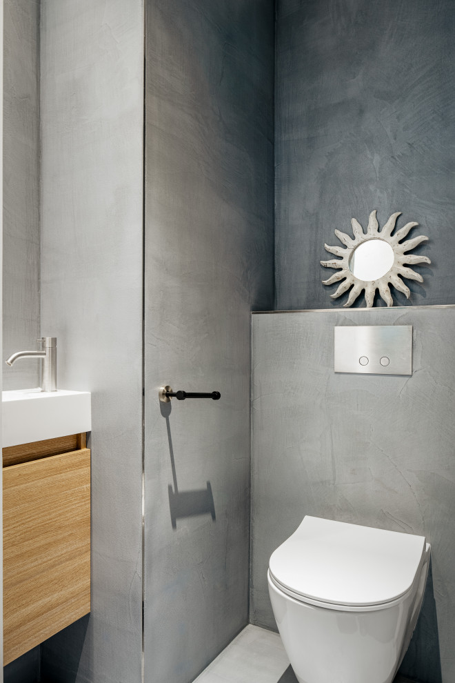 Idéer för ett toalett, med skåp i ljust trä, en vägghängd toalettstol, grå väggar, betonggolv och grått golv