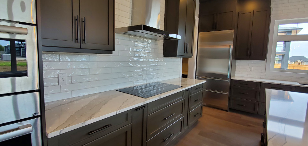 Example of a large trendy l-shaped medium tone wood floor and gray floor eat-in kitchen design in Edmonton with an undermount sink, shaker cabinets, gray cabinets, quartz countertops, white backsplash, ceramic backsplash, stainless steel appliances, an island and multicolored countertops