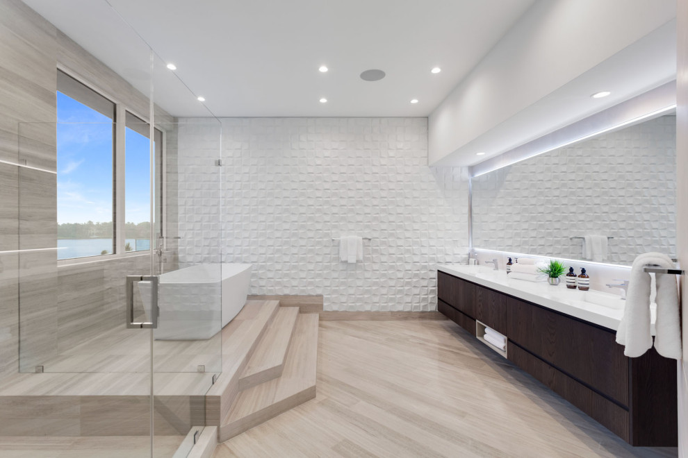 Large modern master bathroom in Miami with flat-panel cabinets, dark wood cabinets, a freestanding tub, a corner shower, a one-piece toilet, white tile, porcelain tile, grey walls, travertine floors, an integrated sink, engineered quartz benchtops, grey floor, a hinged shower door, white benchtops, an enclosed toilet, a double vanity and a floating vanity.