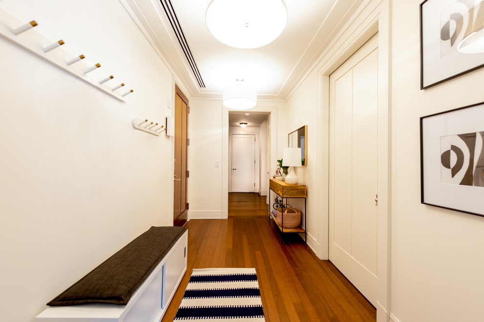 Inspiration for a transitional hallway in New York with white walls, medium hardwood floors and brown floor.